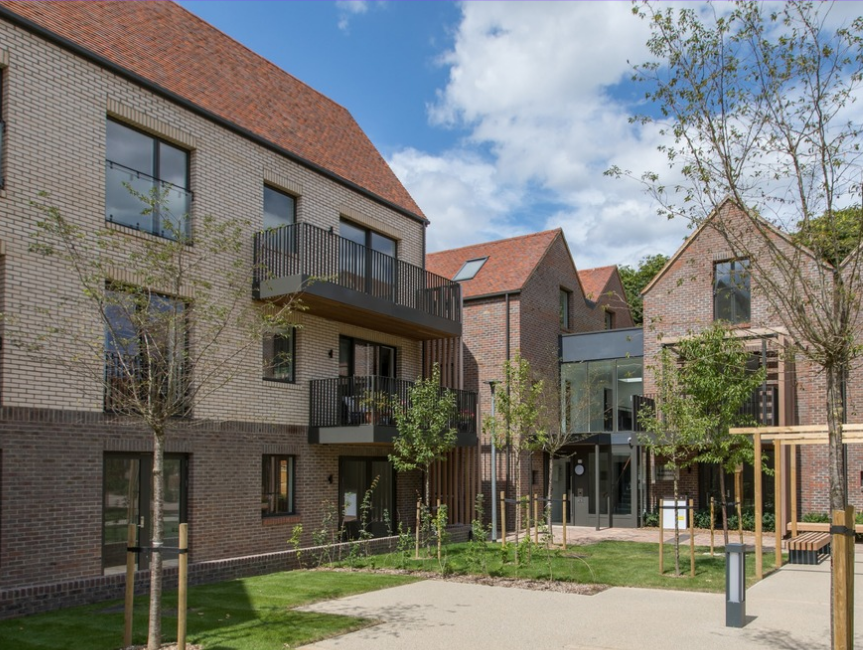 Courtyard of modern brick townhomes with balconies and shared green space in Rivulet